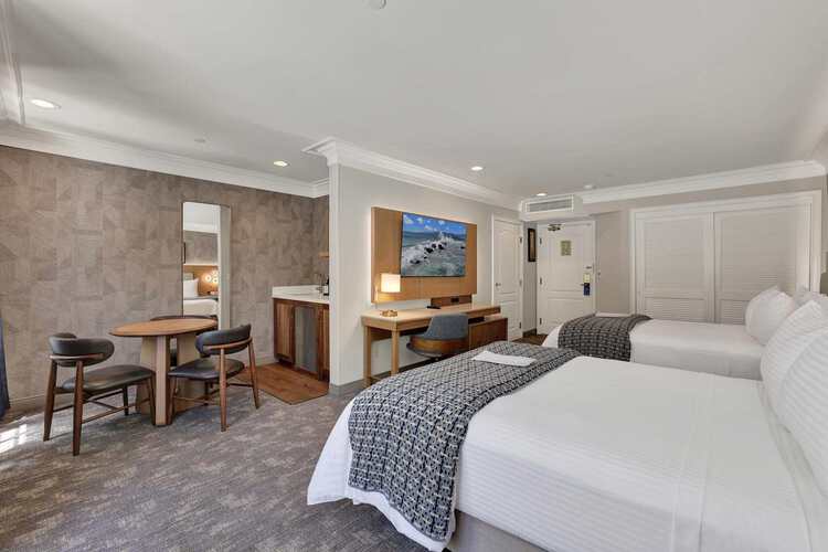 Guest room with two queen beds, a dining area, and a work desk